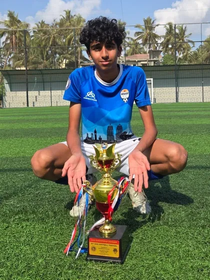 A U14 player squats proudly behind the championship trophy.