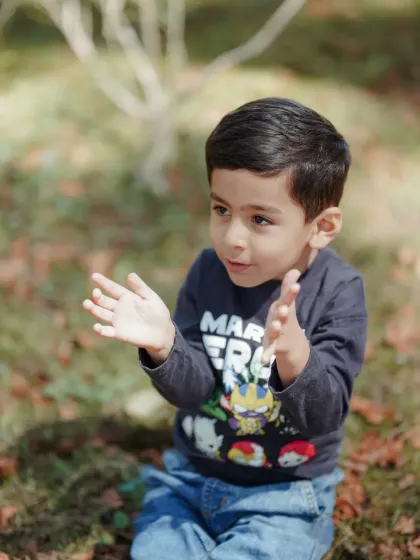 A moment of excitement and expression. This candid shot captures the animated personality of a young boy as he plays and interacts during his family's outdoor photo session.