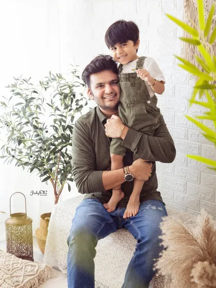 A proud father holding his son. The coordinated green and denim outfits look great in the natural, earthy tones of my boho studio setup.