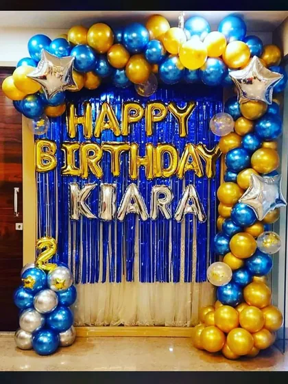 A beautiful balloon arch decoration for a birthday girl named Kiara. The blue and gold chrome balloons with a shimmer curtain create a rich and celebratory look.