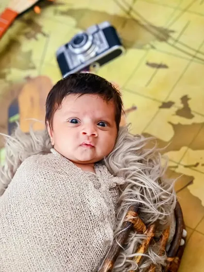 A newborn wrapped in a swaddle lies on a world map, ready for life's big adventures.