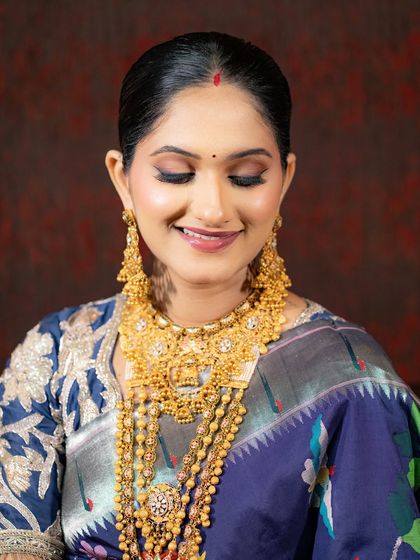 A close-up of the soft matte eye makeup and flawless skin. The look is fresh and radiant, letting the bride's natural beauty and the stunning gold jewelry take center stage.