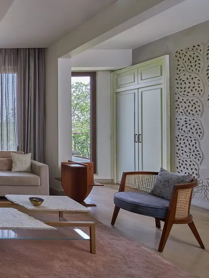 We use architectural details like this 'Tree of Life' jali partition to create a beautiful play of light and pattern. In this living room from the Magnolia Residence, it separates the prayer area, casting intricate shadows that add a layer of tranquility to the space.