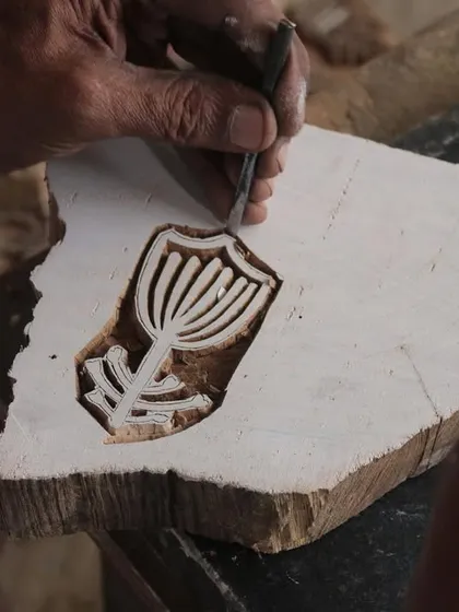 A close-up of a master carver's hands bringing a floral design to life on a teak block. This particular block was created for a collaborative workshop with the Fabric Workshop Museum in Philadelphia.