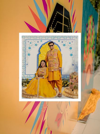 A creative portrait of the couple, framed by the colorful and artistic decor of their Haldi event. This shot highlights the festive and personalized atmosphere.