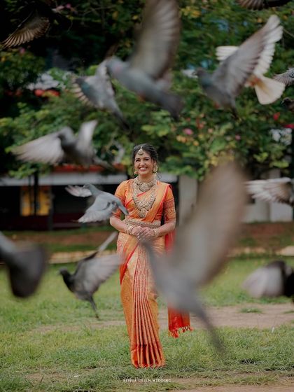 A magical moment as the bride stands amidst a flock of pigeons, her smile serene and confident. This shot has a beautiful, cinematic quality.