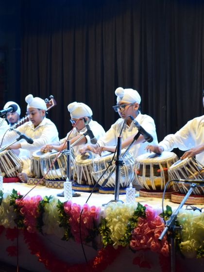 A powerful image of our tabla ensemble in perfect sync during a classical concert. We teach our students that rhythm is born from the silence between the notes.
