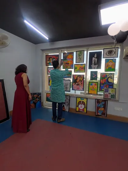 A member of our team carefully arranging paintings for the exhibition. We take great care in presenting each piece professionally, honoring the effort and creativity of every student artist.