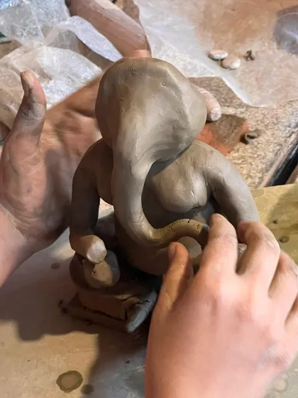 Two pairs of hands working together to shape the Ganesha idol. It's a beautiful process of learning and creating as a community.