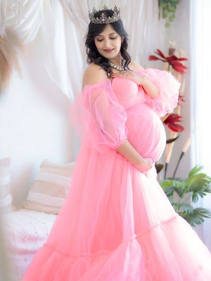 A dreamy and ethereal portrait in a soft pink off-the-shoulder gown. The natural light from the window adds a beautiful glow, making this a truly magical shot.