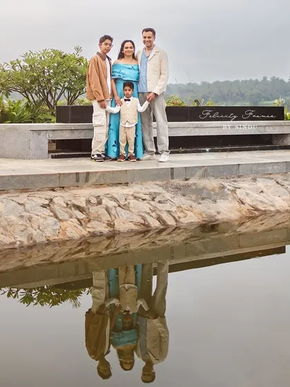 A creative family portrait with their reflection captured in the water below. This image showcases a unique perspective from an outdoor session in a beautiful park.