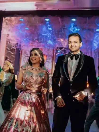The happy couple making their grand entrance, surrounded by dancers and guests, ready to kick off their sangeet party.