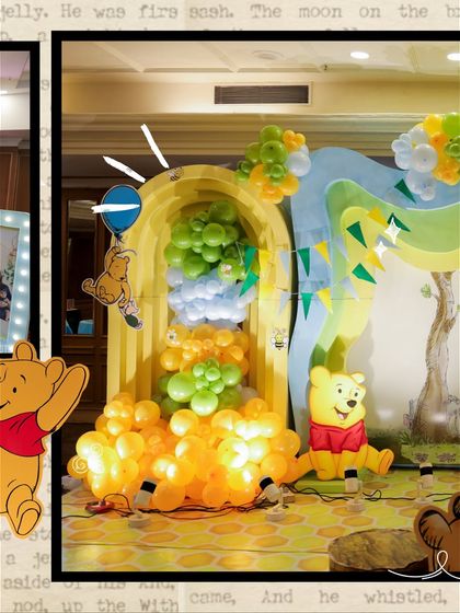 A fun photo spot within the Winnie the Pooh setup, where a balloon waterfall flows from a yellow archway, with Pooh Bear sitting at the bottom.