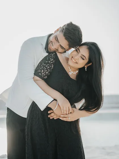 A candid and joyful embrace, capturing the couple's genuine smiles and affection in the warm sunlight.