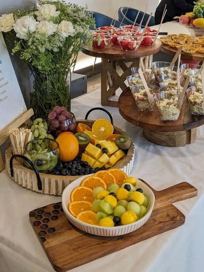 A healthy and refreshing spread for The Wellness Co. event, featuring multiple tiers of fresh fruit salads, watermelon and feta cups, and a large fruit platter.