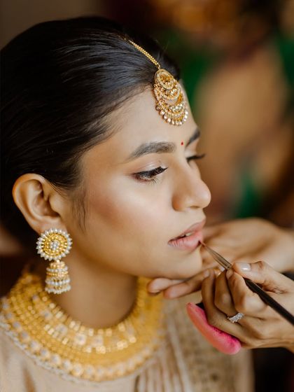 A crucial part of my teaching is the detailed application of makeup, as shown here with the lip color for a South Indian bride. Precision is key for a polished finish.