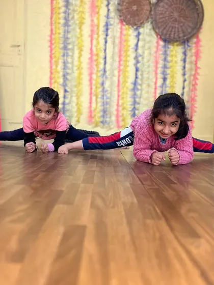 Two students practicing their center splits together. The supportive and friendly environment in our classes encourages students to motivate each other.