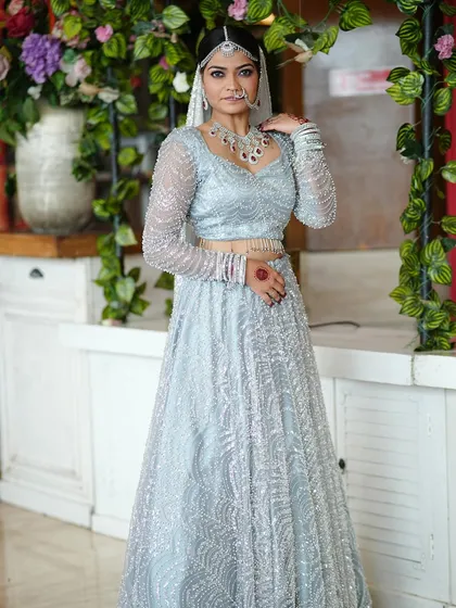 A full view of a modern bridal look. This bride is wearing a stunning silver-grey lehenga with intricate beadwork. I created a soft glam makeup look with a hint of purple on the eyes to match the cool tones of her outfit.
