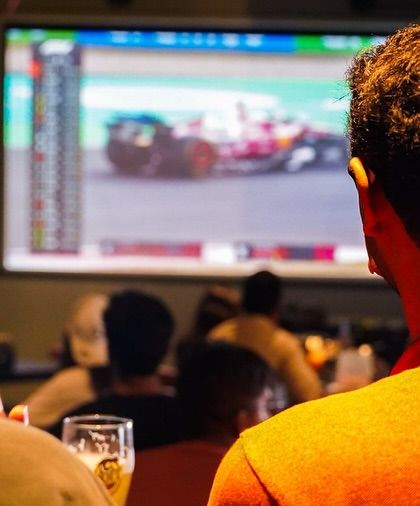Eyes glued to the screen. The tension and excitement of a live F1 race are best experienced with a cold beer and a great crowd.
