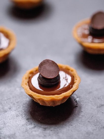 A close-up of our mini salted caramel tarts. The rich, smooth caramel filling is encased in a buttery pastry shell, creating a perfect mouthful.
