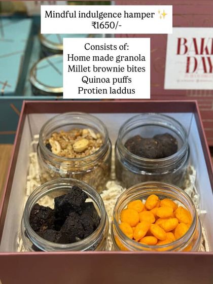 The Mindful Indulgence Hamper menu. A healthy and delicious option consisting of homemade granola, millet brownie bites, quinoa puffs, and protein laddoos.