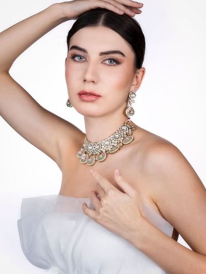 An ethereal and delicate portrait. The soft, high-key lighting and the simple white tulle create a pure and angelic look, with all the focus on the model's serene expression and the beautiful jewelry.