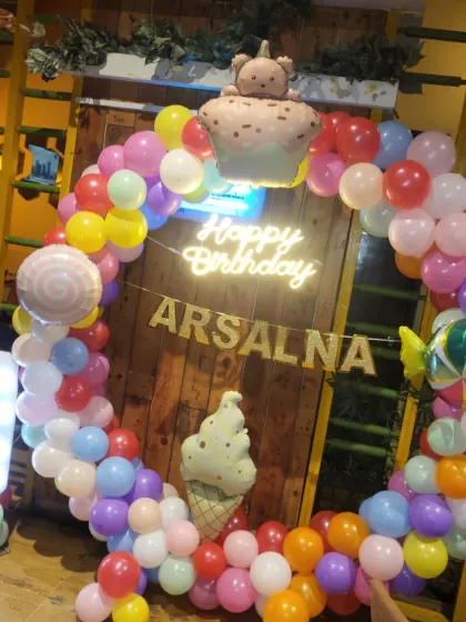 A sweet and colorful Candyland theme for Arsalna's 3rd birthday. This setup features a vibrant circular balloon arch, a custom "Happy Birthday" neon sign, and fun foil balloons like ice cream cones and candy. The light-up marquee number '3' makes the birthday girl feel extra special.