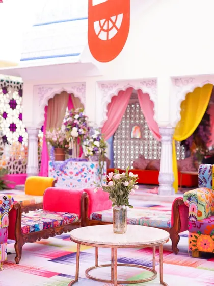 A comfortable and stylish seating area with colorful, eclectic furniture. The mix of patterns and bright colors on the sofas and the floor creates a joyful and welcoming space for guests.