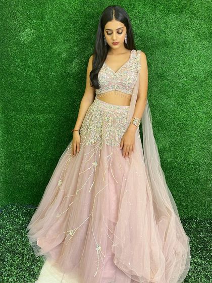 A soft and dreamy pastel pink lehenga. The delicate embroidery and net fabric create a romantic look, perfect for an engagement ceremony or daytime wedding.