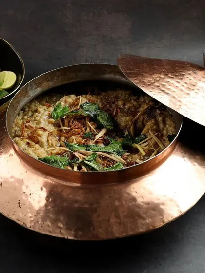 Rich and hearty Haleem served in a hammered copper pot, styled for a Ramzan special menu.