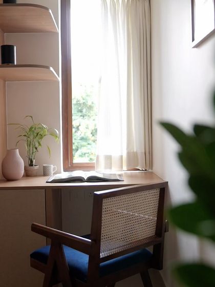 A view of the study desk from the back, highlighting the beautiful cane work on the chair and the natural light streaming in from the window.