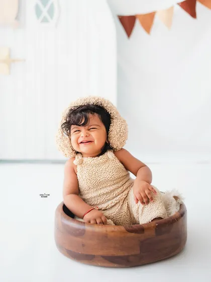 A big, scrunchy-nosed smile from this adorable baby in a teddy bear bonnet.