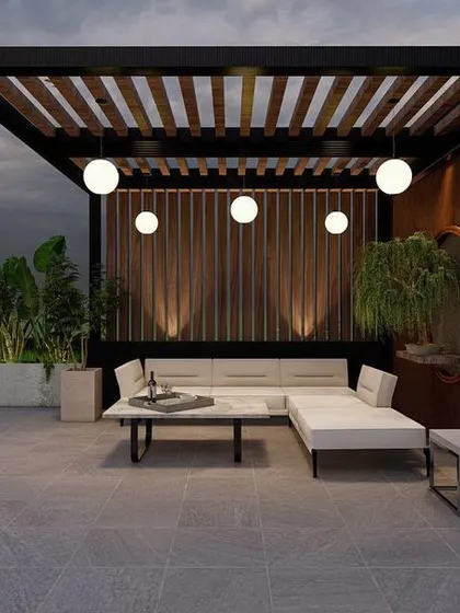 A modern terrace design for a project in Greater Kailash, featuring a sleek pergola with globe lights. The minimalist furniture and wood-paneled accent wall create a contemporary and serene seating area.