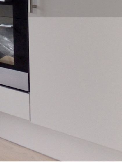 A close-up of a cabinet panel next to an integrated oven, showing the precision and seamless fit that is characteristic of my factory-finished modular kitchens.