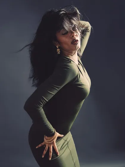 A high-energy pose with dramatic hair movement, creating a sense of wild elegance.