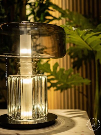 An elegant table lamp designed with a fluted crystal base and a smoked glass upper shade. This piece combines classic materials with a modern form to create a sophisticated light source for a living room or bedroom.