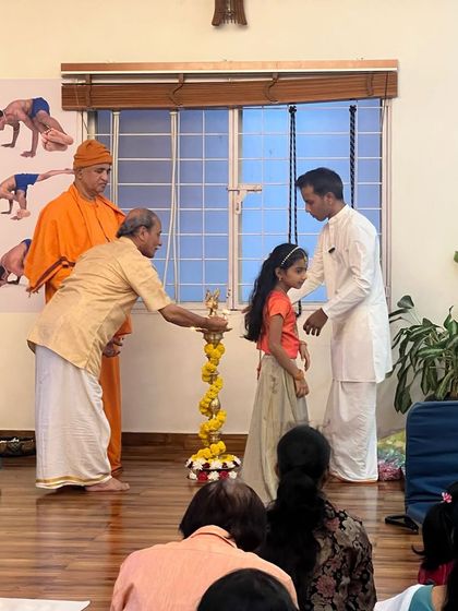 The next generation also participates in our traditions. Here, a young student joins in lighting the lamp. It is important to involve children in these rituals to instill in them a deep-rooted connection to our culture and spiritual path.