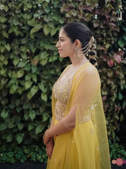 A profile shot showcasing the bride's elegant hairstyle and the intricate hair accessory woven into her braid.
