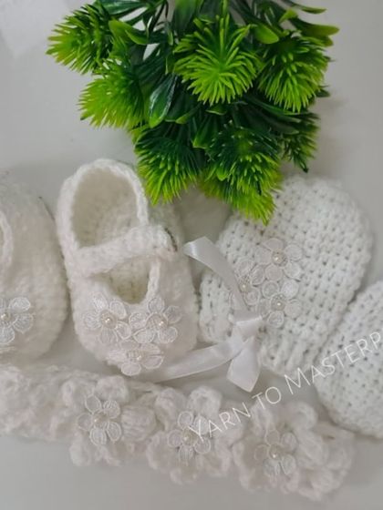 The complete three-piece baptism set, including the lace flower booties, matching mittens, and a coordinating headband, all in pure white.