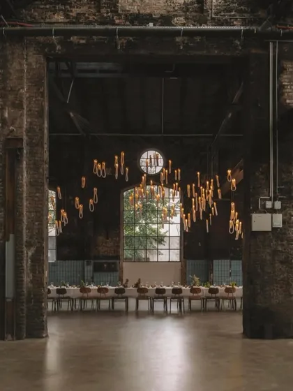 An atmospheric shot of the Bocci 87 installation in a vast, raw space. The warm light from the looped pendants creates a sense of intimacy and grandeur simultaneously.
