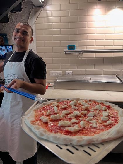 Ready for the oven. Holding a freshly topped pizza on the peel is a moment of anticipation before the fire transforms it.