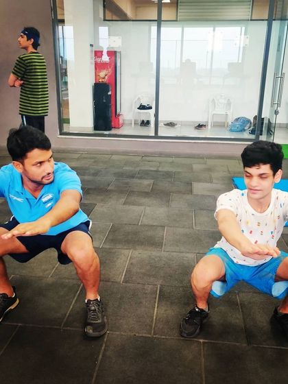 Our head coach demonstrates proper squat form alongside a young athlete. Functional fitness is a critical part of our curriculum to improve stability and endurance.