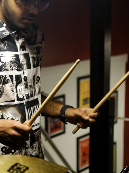 Our drum instructor holding a pair of sticks, ready to teach. Our faculty are passionate musicians dedicated to sharing their knowledge.