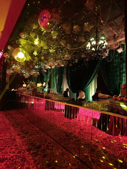 The bar area, where a mirrored front reflected the 'Jungle Disco' theme. The ceiling was a dense canopy of foliage and disco balls, creating a sparkling, festive atmosphere for the cocktail night.
