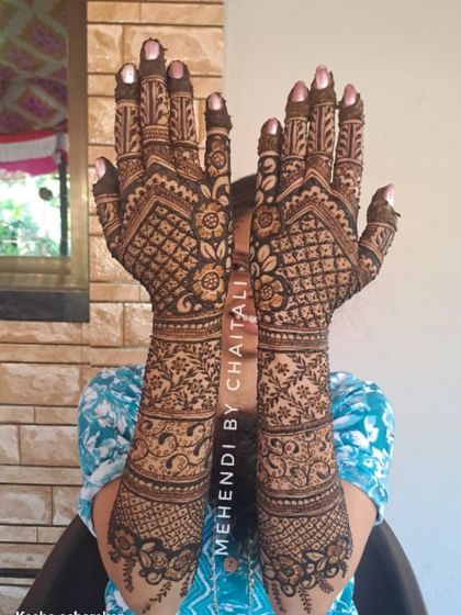 The back of the hands for a bridal mehendi, featuring dense, symmetrical patterns that cover the hands and arms completely for a rich and traditional look.