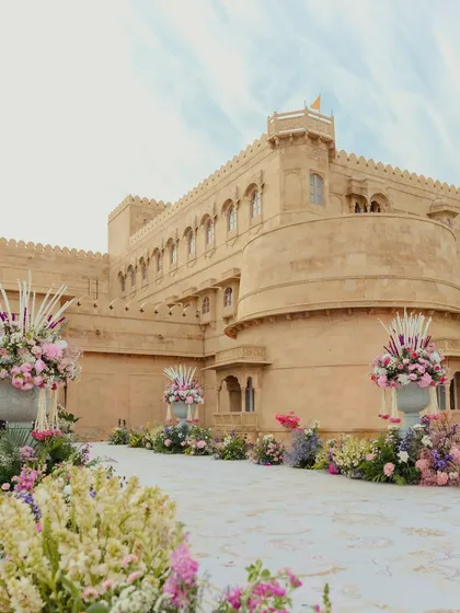 The grand aisle leading to the Suryagarh palace entrance, lined with massive urns of pastel flowers, setting a majestic and romantic tone for the wedding.