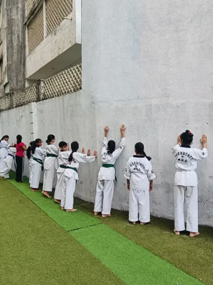 A full line of students doing wall stretches. This is a great way to warm up the shoulders and upper back before practicing punches and blocks.