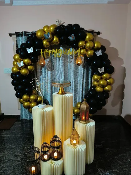 This black and gold balloon ring is enhanced with butterfly details and candle-lit lanterns on the pedestals. This creates a warm, intimate, and elegant atmosphere for a home celebration.