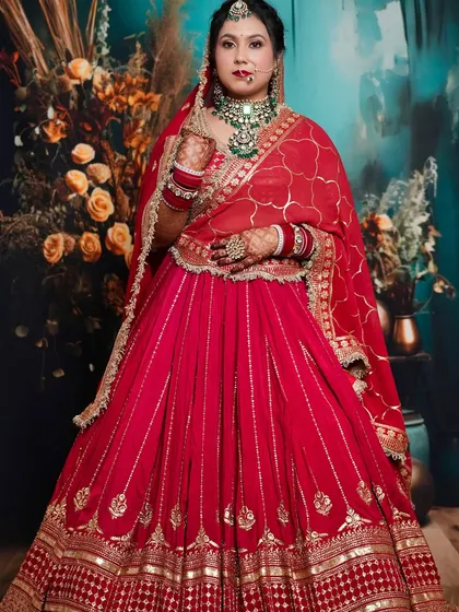 The bride stands tall, showcasing the elegant red lehenga and the flawless makeup that enhances her natural beauty. A proud student moment.