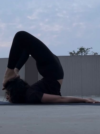 Practicing Karnapidasana (Knee to Ear Pose) on a rooftop. This deep forward bend and inversion provides a powerful stretch for the entire spine.